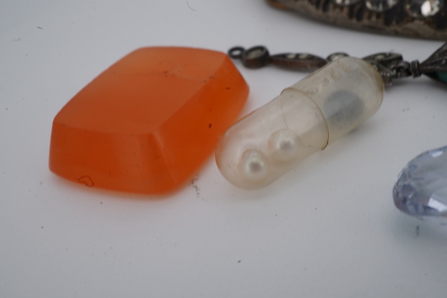 A collection of jewels and a loose sapphire, comprising: a shoe buckle set with colourless pastes, length 6.8cm; a green paste and marcasite pendant imitating jadeite; a polished slab of carnelian; a loose cushion-shaped